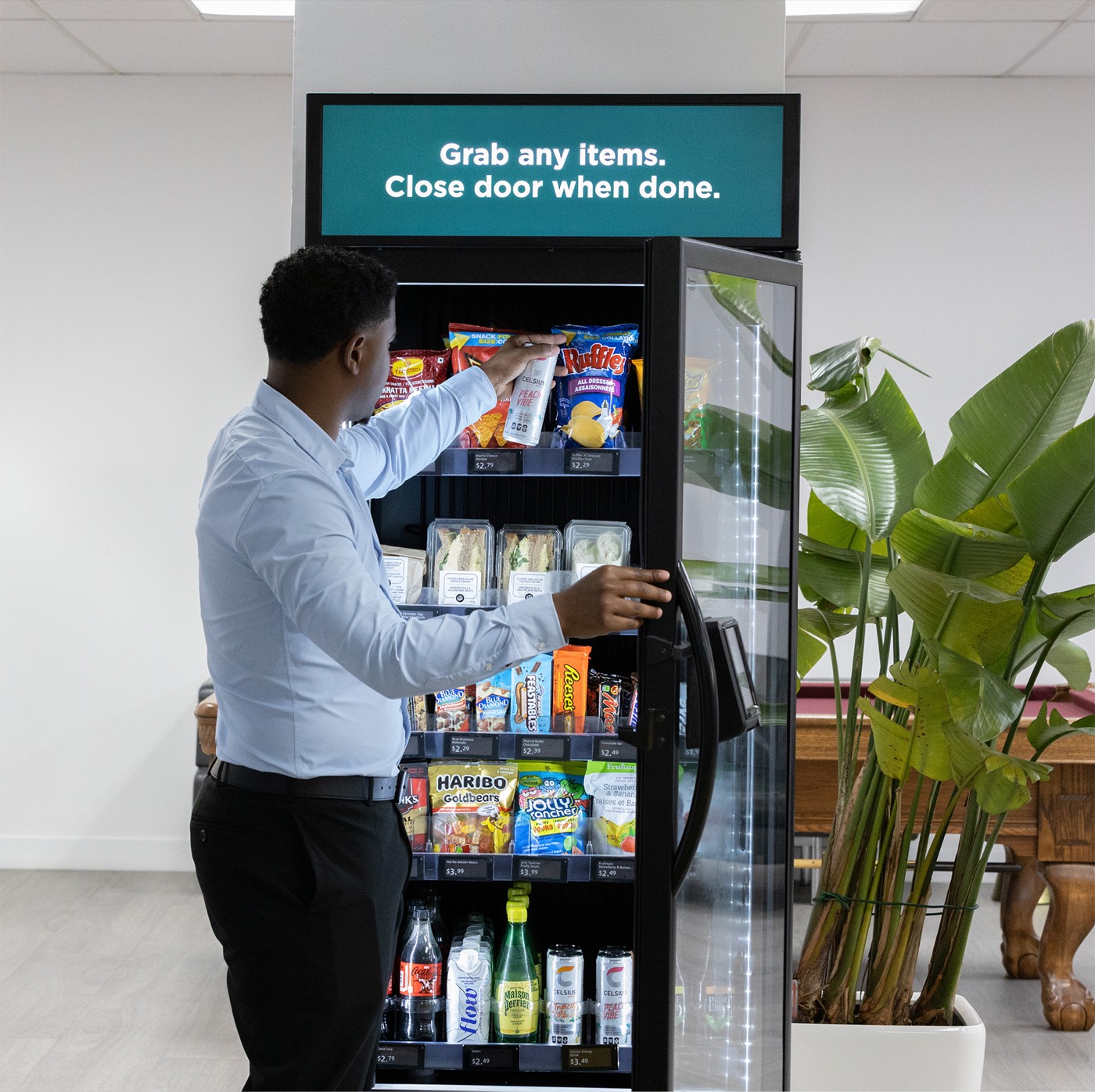 Person grabbing a snack from a VendBeast smart cooler in an office lobby